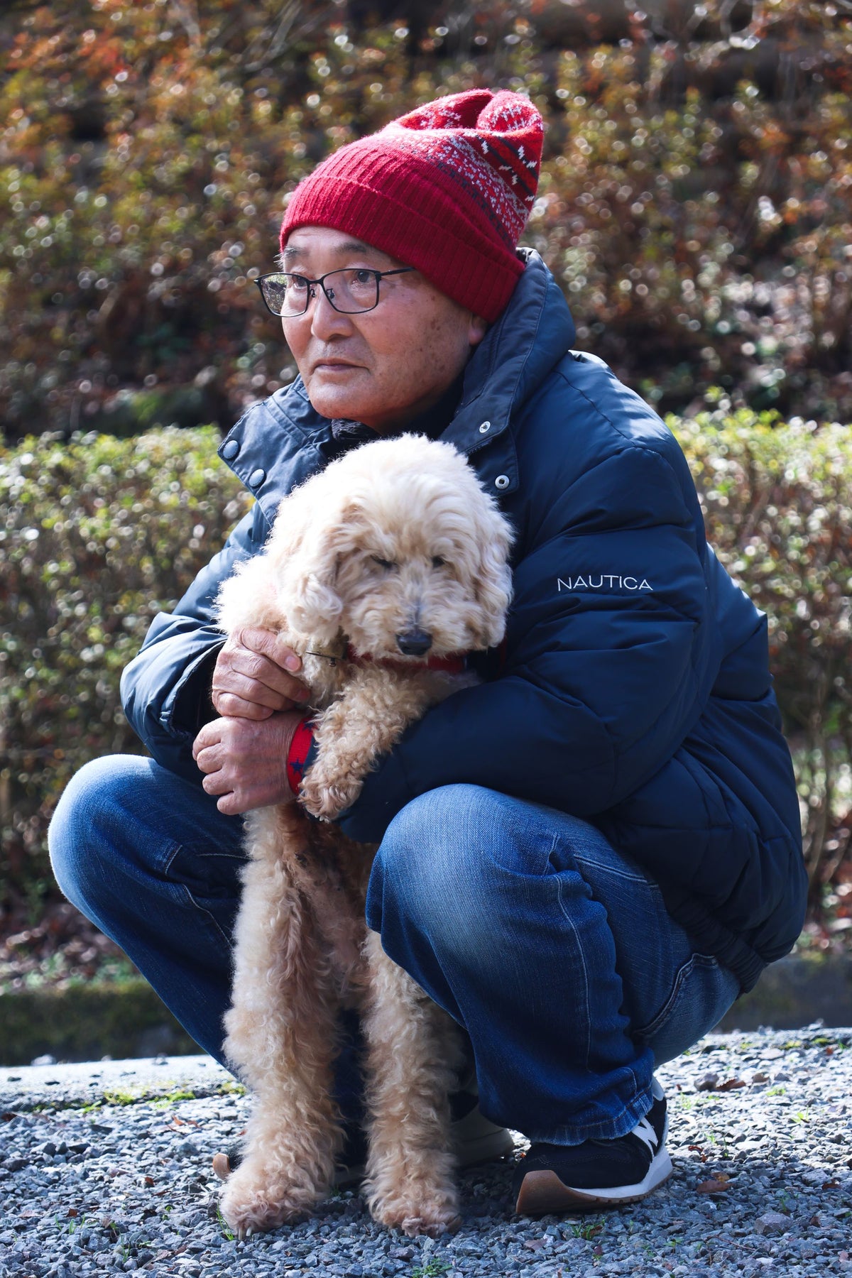 Persona mayor con gorro de lana abrazando a su perro